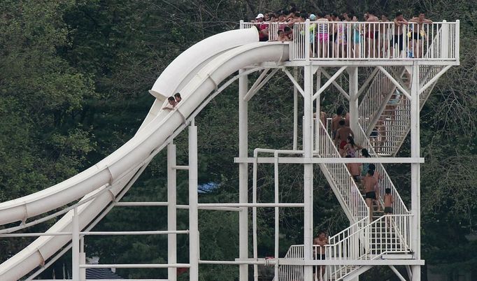 North Koreans line up to slide down a water chute into the swimming pool at an amusement park on the banks of Yalu River, near the North Korean town of Sinuiju, opposite