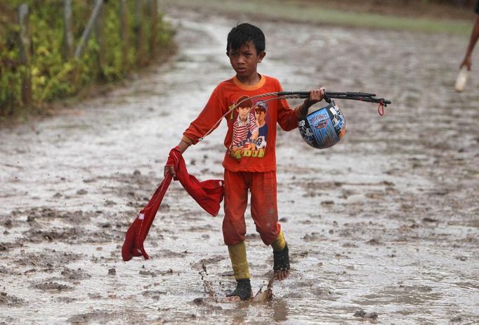 A child jockey walks on the track at Panda racecourse outside Bima, November 17, 2012. Dozens of child jockeys, some as young as eight-years-old take part in the races. Involving nearly 600 horses they take place around a dusty, oval track of 1,400 meters (nearly one mile). The reward, for the winner is a handful of cash for his family, and glory for the jockey. The grand prize is one million rupiah ($100). Those who win their groups get two cows. The chairman of the races' organising team, Hajji Sukri, denies that there is any danger to the children saying they are all skilful riders and none has been killed or seriously hurt. Picture taken November 17, 2012. REUTERS/Beawiharta (INDONESIA - Tags: SPORT SOCIETY) ATTENTION EDITORS: PICTURE 20 of 25 FOR PACKAGE 'BETTING ON CHILD JOCKEYS' Published: Lis. 24, 2012, 9:16 dop.