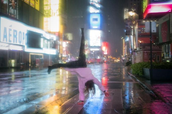 A visitor in a bathrobe does a cartwheel in the rain while visiting Times Square in New York October 29, 2012. As Hurricane Sandy aimed straight for them, promising to hammer the place they live with lashing winds and extensive flooding, New Yorkers seemed to be all about nonchalance on Monday morning - an attitude that didn't last into the afternoon. REUTERS/Adrees Latif (UNITES STATES - Tags: ENVIRONMENT DISASTER SOCIETY TPX IMAGES OF THE DAY) Published: Říj. 30, 2012, 12:34 dop.