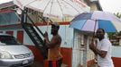 Jamaicans shelter themselves from the rain of approaching Hurricane Sandy in Kingston October 24, 2012. Hurricane Sandy raced toward the southern coast of Jamaica on Wednesday and is expected to make landfall later in the day, the U.S. National Hurricane Center said. A hurricane warning was in effect for both Jamaica and Cuba, although forecasters said Sandy is expected to be a weak Category One hurricane on the five-step Saffir-Simpson scale of hurricane intensity, with winds topping out at 80 mph (130 kph). REUTERS/Gilbert Bellamy (JAMAICA - Tags: ENVIRONMENT DISASTER) Published: Říj. 24, 2012, 4:28 odp.