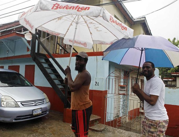 Jamaicans shelter themselves from the rain of approaching Hurricane Sandy in Kingston October 24, 2012. Hurricane Sandy raced toward the southern coast of Jamaica on Wednesday and is expected to make landfall later in the day, the U.S. National Hurricane Center said. A hurricane warning was in effect for both Jamaica and Cuba, although forecasters said Sandy is expected to be a weak Category One hurricane on the five-step Saffir-Simpson scale of hurricane intensity, with winds topping out at 80 mph (130 kph). REUTERS/Gilbert Bellamy (JAMAICA - Tags: ENVIRONMENT DISASTER) Published: Říj. 24, 2012, 4:28 odp.