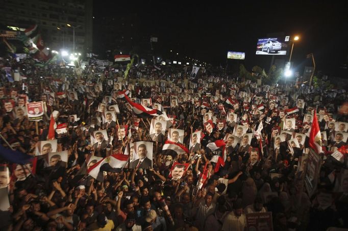 Supporters of Egypt's President Mohamed Mursi, holding his picture, react after the Egyptian army's statement was read out on state TV, at the Raba El-Adwyia mosque square in Cairo July 3, 2013. Egypt's armed forces overthrew elected Islamist President Mursi on Wednesday and announced a political transition with the support of a wide range of political, religious and youth leaders. A statement published in Mursi's name on his official Facebook page after head of Egypt's armed forces General Abdel Fattah al-Sisi's speech said the measures announced amounted to "a full military coup" and were "totally rejected". REUTERS/Khaled Abdullah (EGYPT - Tags: POLITICS CIVIL UNREST TPX IMAGES OF THE DAY) Published: Čec. 3, 2013, 9:21 odp.