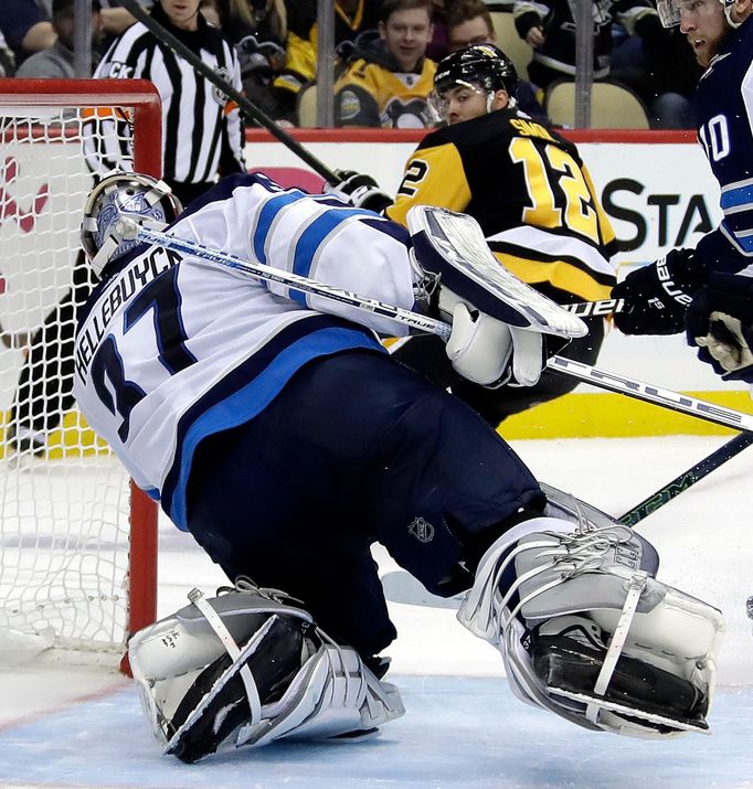 Dominik Simon (12) z Pittsburghu překonává winnipegského brankáře Connora Hellebuycka.