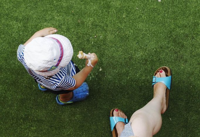 A child eats ice cream with his mother during the hot weather at the South Bank in London August 18, 2012. REUTERS/Luke MacGregor (BRITAIN - Tags: ENVIRONMENT) Published: Srp. 18, 2012, 4:02 odp.