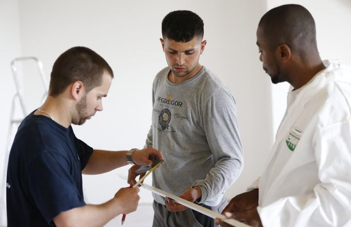 Unemployed Belgian Mohamed Sammar (C) is helped by instructor Michel Bokota (R) and a colleague as he works in a renovation site, part of the "Fit for a job" programme which includes a week-long work placement and aims to consolidate his previous work experience, in Brussels June 19, 2013. Sammar, 27, has been looking for a job in the construction sector for 2 years. "Fit for a job" is the initiative of former Belgian boxing champion Bea Diallo, whose goal was to restore the confidence of unemployed people and help them find a job through their participation in sports. Picture taken June 19, 2013. REUTERS/Francois Lenoir (BELGIUM - Tags: SPORT BOXING SOCIETY BUSINESS EMPLOYMENT) Published: Čec. 5, 2013, 4:29 odp.