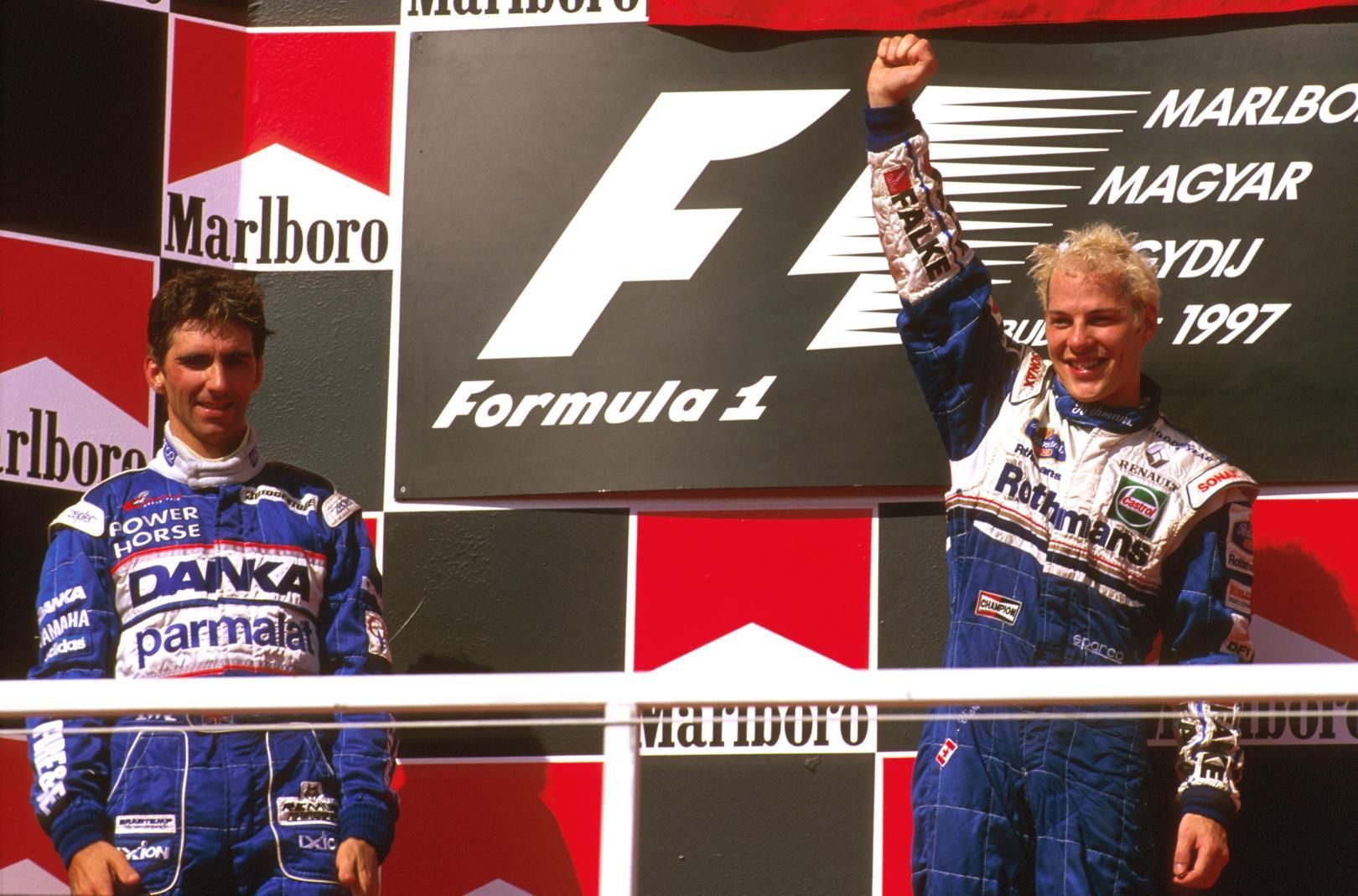 F1: Jacques Villeneuve (vlevo) slaví triumf v GP Maďarka 1997, vedle něj stojí Damon Hill