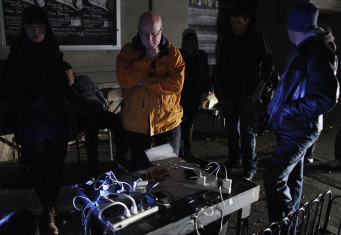 People charge their cell phones at a generator supplied by a local theatre troupe in the Lower East Village in the aftermath of Hurricane Sandy in New York October 31, 2012. The theatre set up a generator, power cords and a table for the community to charge their phones. New York City and the sodden U.S. Northeast began an arduous journey back to normal on Wednesday after mammoth storm Sandy killed at least 64 people in a rampage that swamped coastal cities and cut power to millions. REUTERS/Carlo Allegri (UNITED STATES - Tags: SOCIETY ENVIRONMENT DISASTER) Published: Lis. 1, 2012, 3:54 dop.