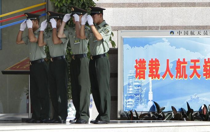 Soldiers adjust their caps while standing guard at an entrance of the Wentiange, Chinese astronauts' apartment building, in Jiuquan Satellite Launch Center, Gansu province, June 16, 2012. China will send its first woman into outer space this week, prompting a surge of national pride as the rising power takes its latest step towards putting a space station in orbit within the decade. Liu Yang, a 33-year-old fighter pilot, will join two other astronauts aboard the Shenzhou 9 spacecraft when it lifts off from a remote Gobi Desert launch site on Saturday evening. REUTERS/Jason Lee (CHINA - Tags: SCIENCE TECHNOLOGY MILITARY) Published: Čer. 16, 2012, 2:36 dop.