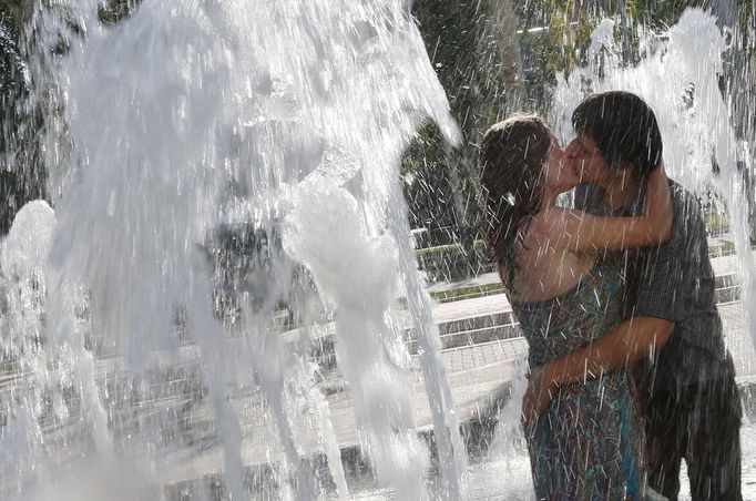 A couple kiss as they cool off in a fountain on a hot summer day in downtown Donetsk June 22, 2012. REUTERS/Alessandro Bianchi (UKRAINE - Tags: ENVIRONMENT SOCIETY) Published: Čer. 22, 2012, 4:32 odp.