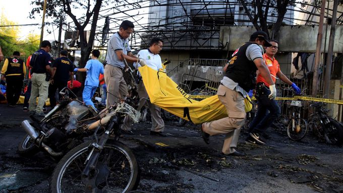 Záchranáři odklízejí tělo po nedělních útocích na tři kostely v indonéském městě Surabaja.