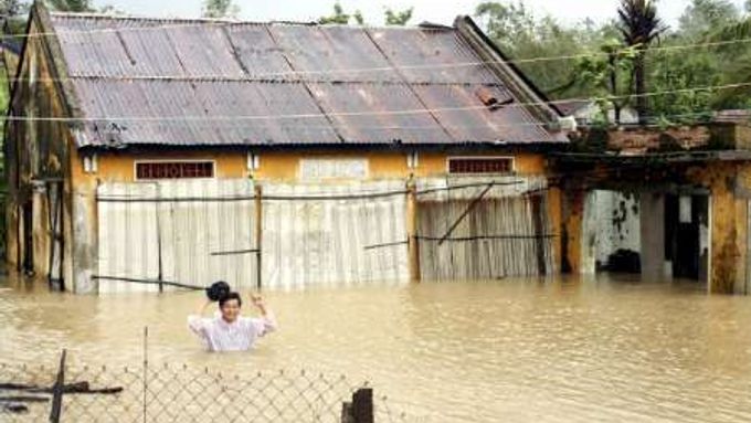 Vietnamec se brodí ke svému domu zatopenému při tropické bouři Mirinae.