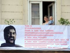 Na snímku žena s dítětem sleduje pochod odborářů z balkónu ve Vítězné ulici v Praze zpoza plakátu, který je hříčkou s filmem 300: Bitva u Thermopyl.