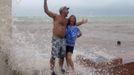 As Tropical Storm Isaac moves over the island, Todd Kjeer and Penny Garbus (R) deliberately stand in the path of breaking waves in Key West August 26, 2012.Tropical Storm Isaac lashed south Florida with winds and heavy rain on Sunday after battering the Caribbean, disrupting plans for the Republican National Convention in Tampaand threatening to interrupt about half of U.S. offshore oil output. REUTERS/Andrew Innerarity (UNITED STATES - Tags: ENVIRONMENT DISASTER) Published: Srp. 26, 2012, 11:22 odp.