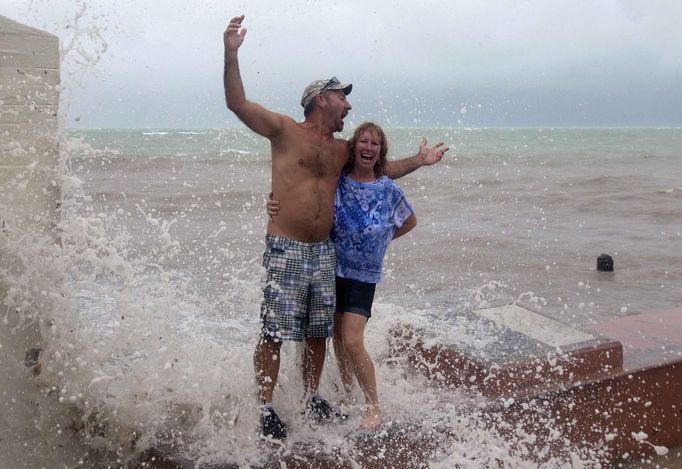 As Tropical Storm Isaac moves over the island, Todd Kjeer and Penny Garbus (R) deliberately stand in the path of breaking waves in Key West August 26, 2012.Tropical Storm Isaac lashed south Florida with winds and heavy rain on Sunday after battering the Caribbean, disrupting plans for the Republican National Convention in Tampaand threatening to interrupt about half of U.S. offshore oil output. REUTERS/Andrew Innerarity (UNITED STATES - Tags: ENVIRONMENT DISASTER) Published: Srp. 26, 2012, 11:22 odp.