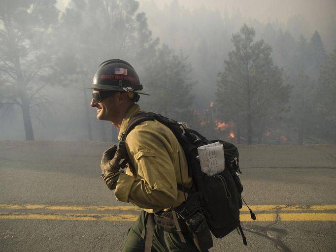 A firefighter walks down a road as the Little Bear Fire burns in the Lincoln National Forest near Ruidoso, New Mexico, in this June 13, 2012 U.S. Forest Service handout photo. Some of the 2,500 people forced to evacuate their central New Mexico houses by wildfires raging near the resort village of Ruidoso began returning home this week with the help of National Guard troops, officials said. Photo taken June 13, 2012. REUTERS/Kari Greer/US Forest Service/Handout (UNITED STATES - Tags: DISASTER ENVIRONMENT) FOR EDITORIAL USE ONLY. NOT FOR SALE FOR MARKETING OR ADVERTISING CAMPAIGNS. THIS IMAGE HAS BEEN SUPPLIED BY A THIRD PARTY. IT IS DISTRIBUTED, EXACTLY AS RECEIVED BY REUTERS, AS A SERVICE TO CLIENTS Published: Čer. 17, 2012, 4:04 dop.