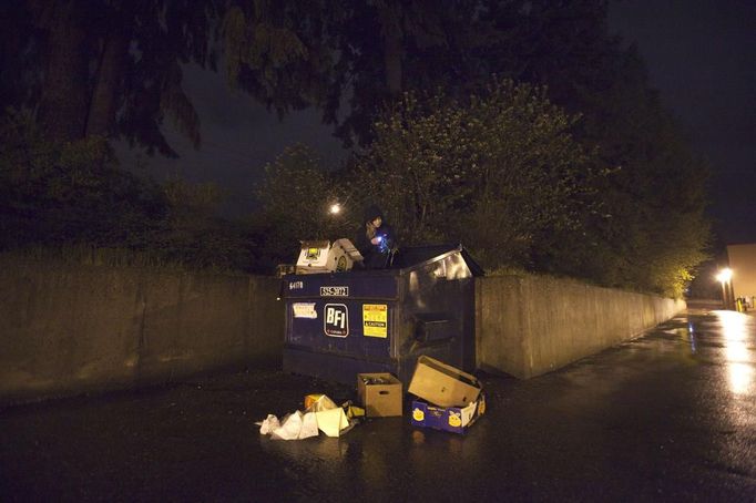 Robin Pickell, 23, a practising 'freegan', sorts through a dumpster for edible food in an alley behind in Vancouver, British Columbia April 26, 2012. A 'freegan' is someone who gathers edible food from the garbage bins of grocery stores or food stands that would otherwise have been thrown away. Freegans aim to spend little or no money purchasing food and other goods, not through financial need but to try to address issues of over-consumption and excess. Picture taken April 26, 2012. REUTERS/Ben Nelms (CANADA - Tags: SOCIETY) ATTENTION EDITORS PICTURE 16 OF 21 FOR PACKAGE 'DUMPSTER DIVING FOR FOOD' Published: Kvě. 15, 2012, poledne