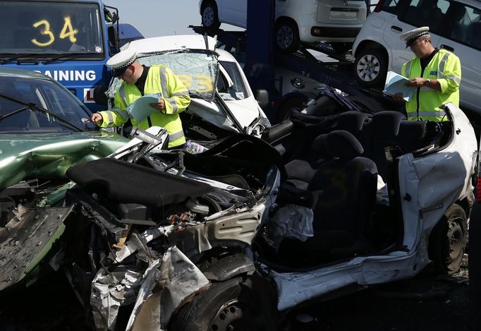 Police officers work amongst the wreckage of some of the 100 vehicles involved in multiple collisions, which took place in dense fog during the morning rush hour, on the Sheppey Bridge in Kent, east of London, September 5, 2013. Eight people were seriously injured and dozens hurt in the multiple crashes.