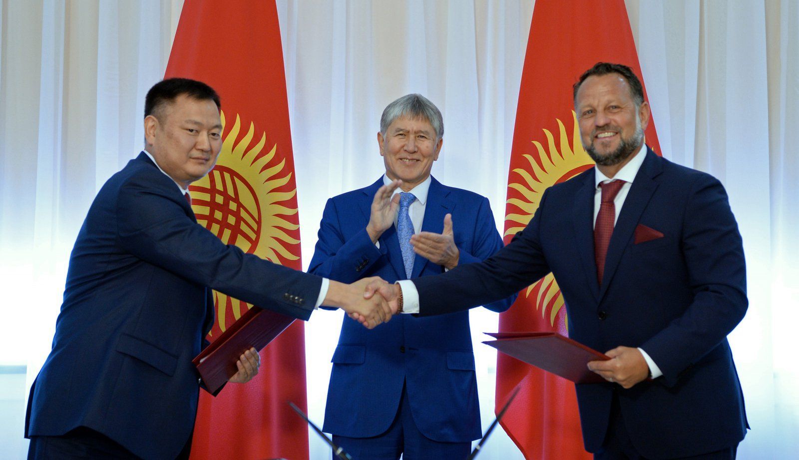 Michael Smelík si podává ruku se zástupcem kyrgyzské vlády. Tleská jim prezident Almazbek Atambajev.