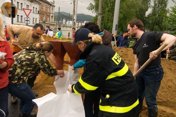 Hasiči naplňují pytle pískem