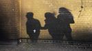 A shadow is cast on a wall of George Kapetanios, his wife and their daughter as they walk along a street in Potters Bar, on the outskirts of London