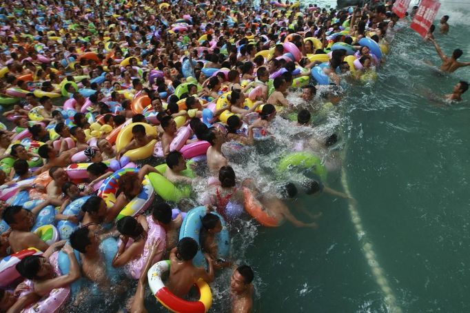 Lifeguards (R) watch visitors crowding an artificial wave pool at a tourist resort to escape the summer heat in Daying county of Suining, Sichuan province August 19, 2012. Picture taken August 19, 2012. REUTERS/Stringer (CHINA - Tags: ENTERTAINMENT ENVIRONMENT TRAVEL TPX IMAGES OF THE DAY) CHINA OUT. NO COMMERCIAL OR EDITORIAL SALES IN CHINA Published: Srp. 20, 2012, 5:52 dop.