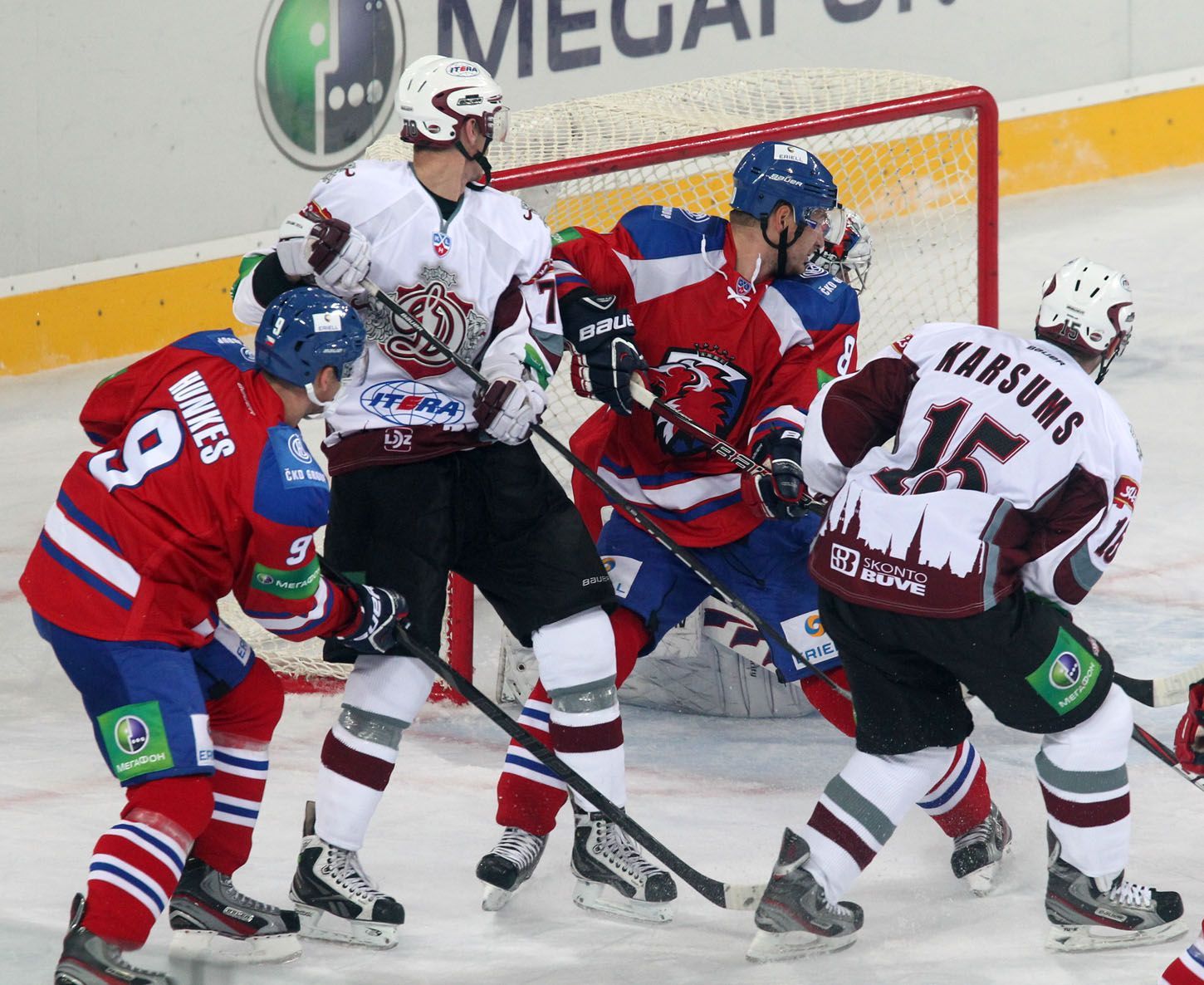 Hokejisté Jiří Hunkes (vlevo) a Michal Sersen (druhý zprava) se snaží bránit Martinse Karsumse (vpravo) v utkání KHL 2012/13 mezi Lvem Praha s Dinamem Riga .