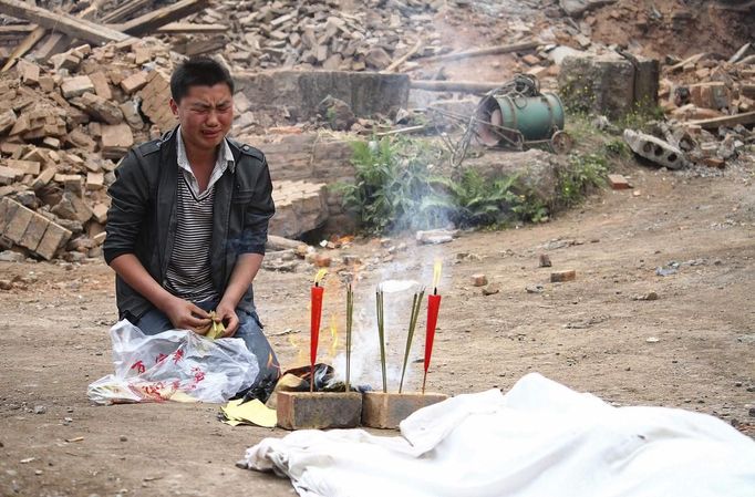 A man cries as he burns offering in front of the body of his relative after Saturday's earthquake, in Qingren township of Lushan county, Sichuan province April 21, 2013. Rescuers struggled to reach a remote, rural corner of southwestern China on Sunday as the toll of the dead and missing from the country's worst earthquake in three years climbed to 208 with almost 1,000 serious injuries. The 6.6 magnitude quake struck in Lushan county, near the city of Ya'an in the southwestern province of Sichuan, close to where a devastating 7.9 quake hit in May 2008, killing 70,000. Picture taken April 21, 2013. REUTERS/Stringer (CHINA - Tags: DISASTER SOCIETY) CHINA OUT. NO COMMERCIAL OR EDITORIAL SALES IN CHINA