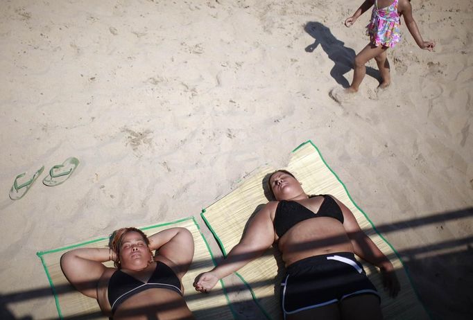 People lie on the beach at Coney Island in the Brooklyn borough of New York June 30, 2012. About 3.9 million homes and businesses were without power on Saturday amid a record heat wave in the eastern United States after deadly thunderstorms downed power lines from Indiana to New Jersey. REUTERS/Eric Thayer (UNITED STATES - Tags: ENVIRONMENT SOCIETY) Published: Čer. 30, 2012, 8:38 odp.