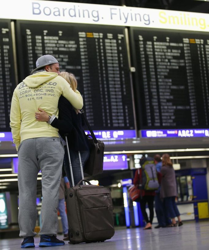 Two passengers hug each other as they look at the flight schedule board at the terminal for German air carrier Lufthansa at the Fraport airport in Frankfurt, August 31, 2012. Lufthansa passengers face widespread flight disruption from Friday after cabin crew representatives said they would start a series of strikes over pay and cost-cutting measures at Germany's largest airline. The UFO union, which represents around two-thirds of Lufthansa's 19,000 cabin crew, late on Thursday called on its members to strike from 0300 GMT to 1100 GMT on Friday in Frankfurt. REUTERS/Kai Pfaffenbach (GERMANY - Tags: BUSINESS EMPLOYMENT CIVIL UNREST TRANSPORT) Published: Srp. 31, 2012, 4:43 dop.