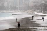 Lidé si drží deštníky, snaží se ochránit před sněhem. Pohled na pláž v Nice.