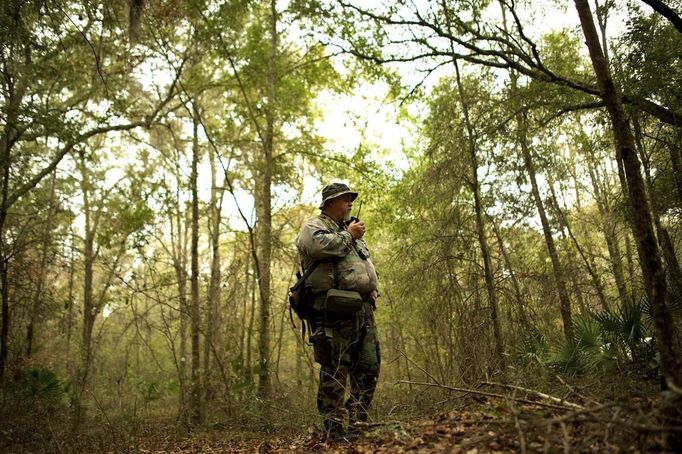 Jim Foster, 57, a retired police officer and leader of the North Florida Survival Group, radios group members to check their status as they perform a land navigation drill during a field training exercise in Old Town, Florida, December 8, 2012. The group trains children and adults alike to handle weapons and survive in the wild. The group passionately supports the right of U.S. citizens to bear arms and its website states that it aims to teach "patriots to survive in order to protect and defend our Constitution against all enemy threats". Picture taken December 8, 2013. REUTERS/Brian Blanco (UNITED STATES - Tags: SOCIETY POLITICS) ATTENTION EDITORS: PICTURE 6 OF 20 FOR PACKAGE 'TRAINING CHILD SURVIVALISTS' SEARCH 'FLORIDA SURVIVAL' FOR ALL IMAGES Published: Úno. 22, 2013, 1 odp.