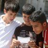 Boys read one of the leaflets dropped by the Syrian army over opposition-held Aleppo districts asking residents to cooperate with the military and calling on fighters to surrender