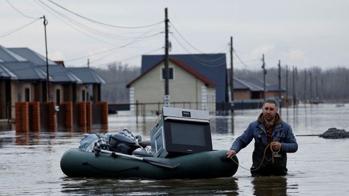 Muž táhne nafukovací člun se svými věcmi po zatopené ulici ve vesnici Ivanovskoje v Orenburské oblasti.