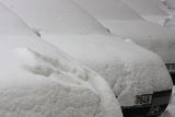 Automobily milosrdně skryty pod vrstvou sněhu.