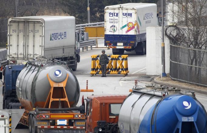 A South Korean soldier keeps watch as South Korean trucks leave the South's CIQ (Customs, Immigration and Quarantine) office to go to the inter-Korean Kaesong Industrial Complex in North Korea, just south of the demilitarised zone separating the two Koreas, in Paju, north of Seoul, April 1, 2013. North Korea said on Saturday it was entering a "state of war" with South Korea, but Seoul and the United States played down the statement as tough talk. Pyongyang also threatened to close a border industrial zone, the last remaining example of inter-Korean cooperation which gives the North access to $2 billion in trade a year. REUTERS/Lee Jae-Won (SOUTH KOREA - Tags: MILITARY POLITICS BUSINESS TRANSPORT) Published: Dub. 1, 2013, 3:02 dop.