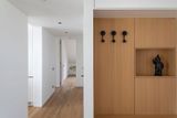 Bílé stěny a dveře s minimalistickým designem doplňují dřevěné vestavby a podlaha.