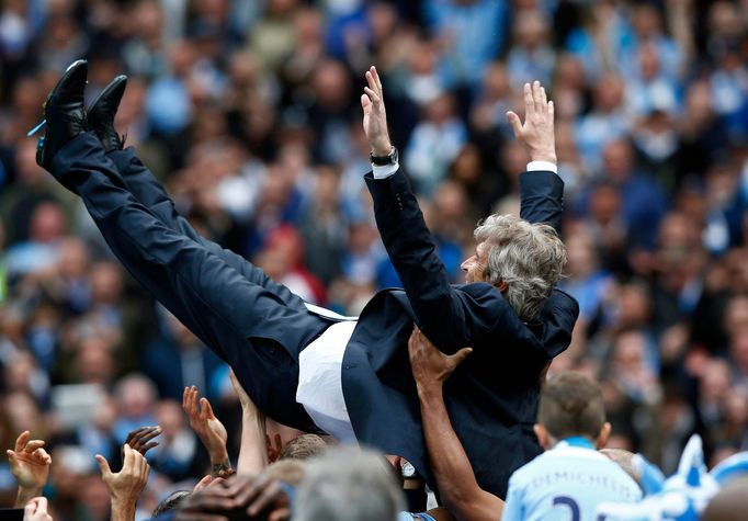 Manchester City's manager Manuel Pellegrini is thrown into the air by his team as they celebrate winning the English Premier League trophy following their soccer match ag