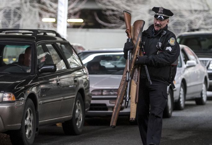 Seattle Police Department Sgt. Paul Gracy carries weapons during a gun buyback event in Seattle, Washington January 26, 2013. Participants received up to a $100 gift card in exchange for working handguns, shotguns and rifles, and up to a $200 gift card for assault weapons. The event lasted from 9 a.m. until shortly after noon, after the event ran out of $80,000 worth of gift cards. REUTERS/Nick Adams (UNITED STATES - Tags: POLITICS CIVIL UNREST) Published: Led. 27, 2013, 12:46 dop.