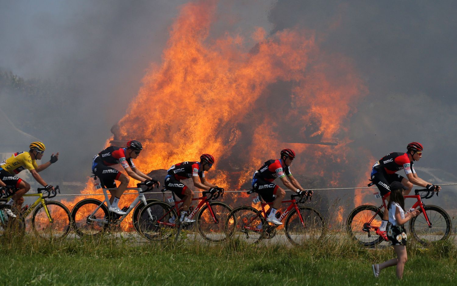 Peloton projíždí kolem hořící slámy v 6. etapě na Tour de France 2018