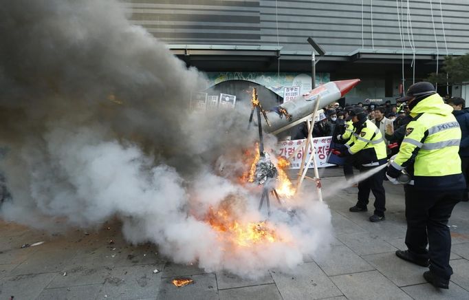 Policemen use fire extinguishers to put out flames after anti-North Korean protesters burned a mock North Korean missile, its flag and an effigy of the North's leader Kim Jong-Un during a protest blaming the North's rocket launch in central Seoul December 12, 2012. North Korea successfully launched a rocket on Wednesday, boosting the credentials of its new leader and stepping up the threat the isolated and impoverished state poses to its opponents. The rocket, which North Korea says put a weather satellite into orbit, has been labelled by the United States, South Korea and Japan as a test of technology that could one day deliver a nuclear warhead capable of hitting targets as far as the continental United States. REUTERS/Lee Jae-Won (SOUTH KOREA - Tags: MILITARY POLITICS SCIENCE TECHNOLOGY CIVIL UNREST)