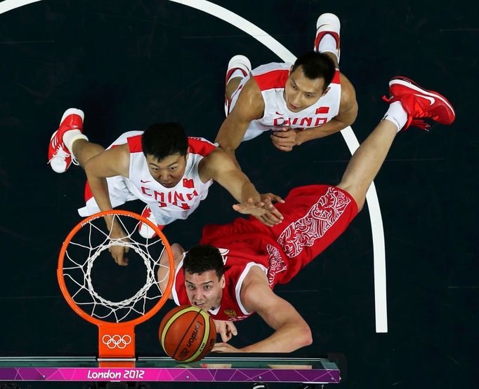 Čínští basketbalisté Wang Žiži (vlevo) a Yi Jianlian brání Rusa Sašu Kauna v utkání skupiny B na OH 2012 v Londýně.