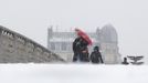 A woman holding an umbrella walks on a snow-covered bridge over the River Seine in Paris March 12, 2013 as winter weather with snow and freezing temperatures returns to northern France. REUTERS/Gonzalo Fuentes (FRANCE - Tags: ENVIRONMENT) Published: Bře. 12, 2013, 2:32 odp.