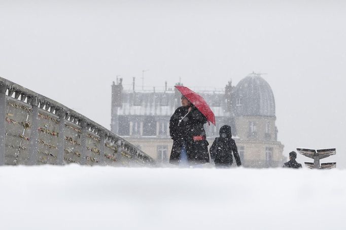 A woman holding an umbrella walks on a snow-covered bridge over the River Seine in Paris March 12, 2013 as winter weather with snow and freezing temperatures returns to northern France. REUTERS/Gonzalo Fuentes (FRANCE - Tags: ENVIRONMENT) Published: Bře. 12, 2013, 2:32 odp.