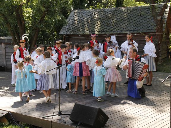 Učitel Vlastimil Ondra s harmonikou a s dětmi ze svého folklorního souboru Nivnička na folklorním festivalu ve Strážnici