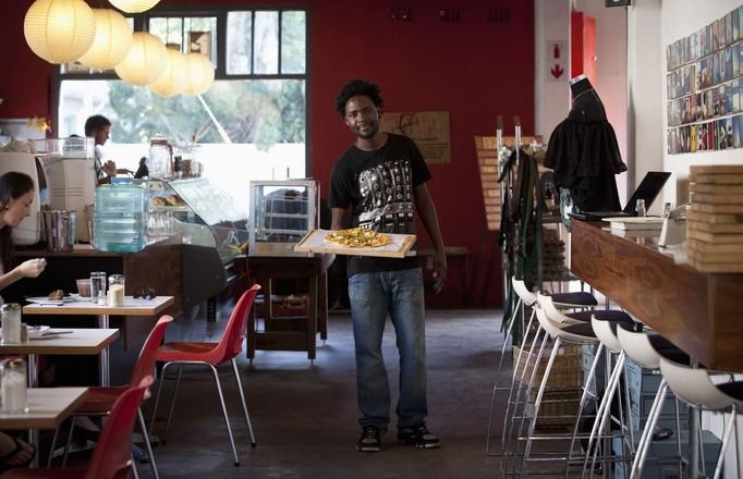 Terence Kamanda, a 25 year-old waiter, poses for a picture as he serves customers in The Corner Cafe restaurant in Durban, April 26, 2012. The Zimbabwean national studied for 18 months at the London Chamber of Commerce Institute College in Gweru, Zimbabwe, where he received a diploma in marketing. He hoped to find a job in marketing but has been working as a waiter for eight months.