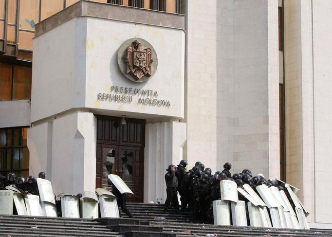 Policie schovaná za plechovými štíty brání před demonstranty prezidentskou kancelář.