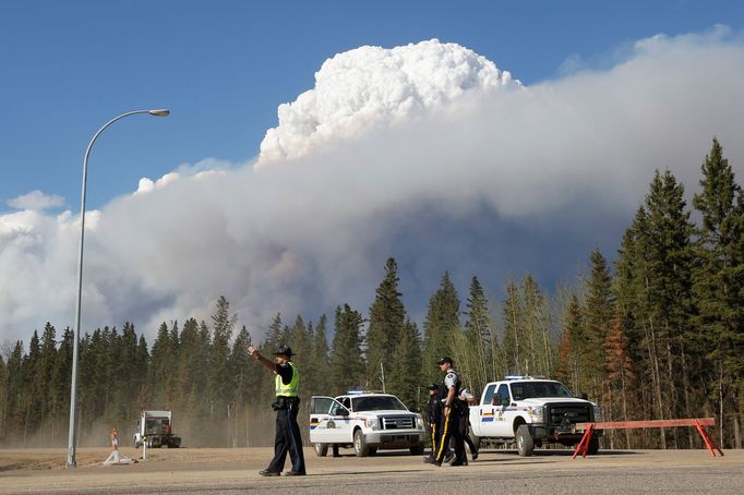 Policisté na cestě vedoucí z Fort McMurray dohlížejí na evakuaci.