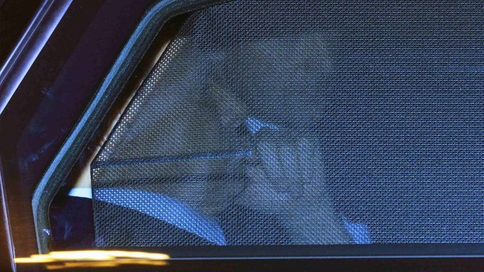 Berlusconi telefonuje na zadním sedadle svého automobilu.