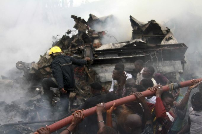 People help rescue workers lift a water hose to extinguish a fire after a plane crashed into a neighbourhood in Ishaga district, an outskirt of Nigeria's commercial capital Lagos June 3, 2012. There were no survivors among the 147 people on board a domestic passenger aircraft that crashed in the Nigerian city of Lagos on Sunday, an official of the National Emergency Management Agency (NEMA), told Reuters. REUTERS/Akintunde Akinleye (NIGERIA - Tags: DISASTER TRANSPORT) Published: Čer. 3, 2012, 9:47 odp.