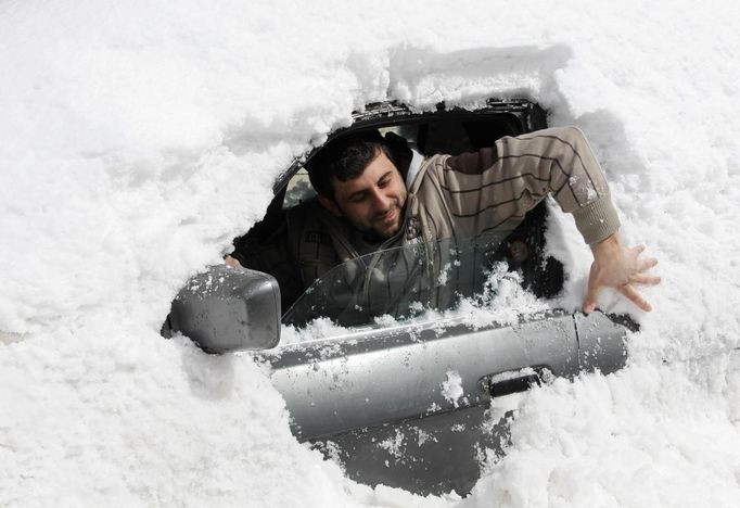 A man removes snow covering his car after a heavy snowstorm in the Aley area, eastern Lebanon.